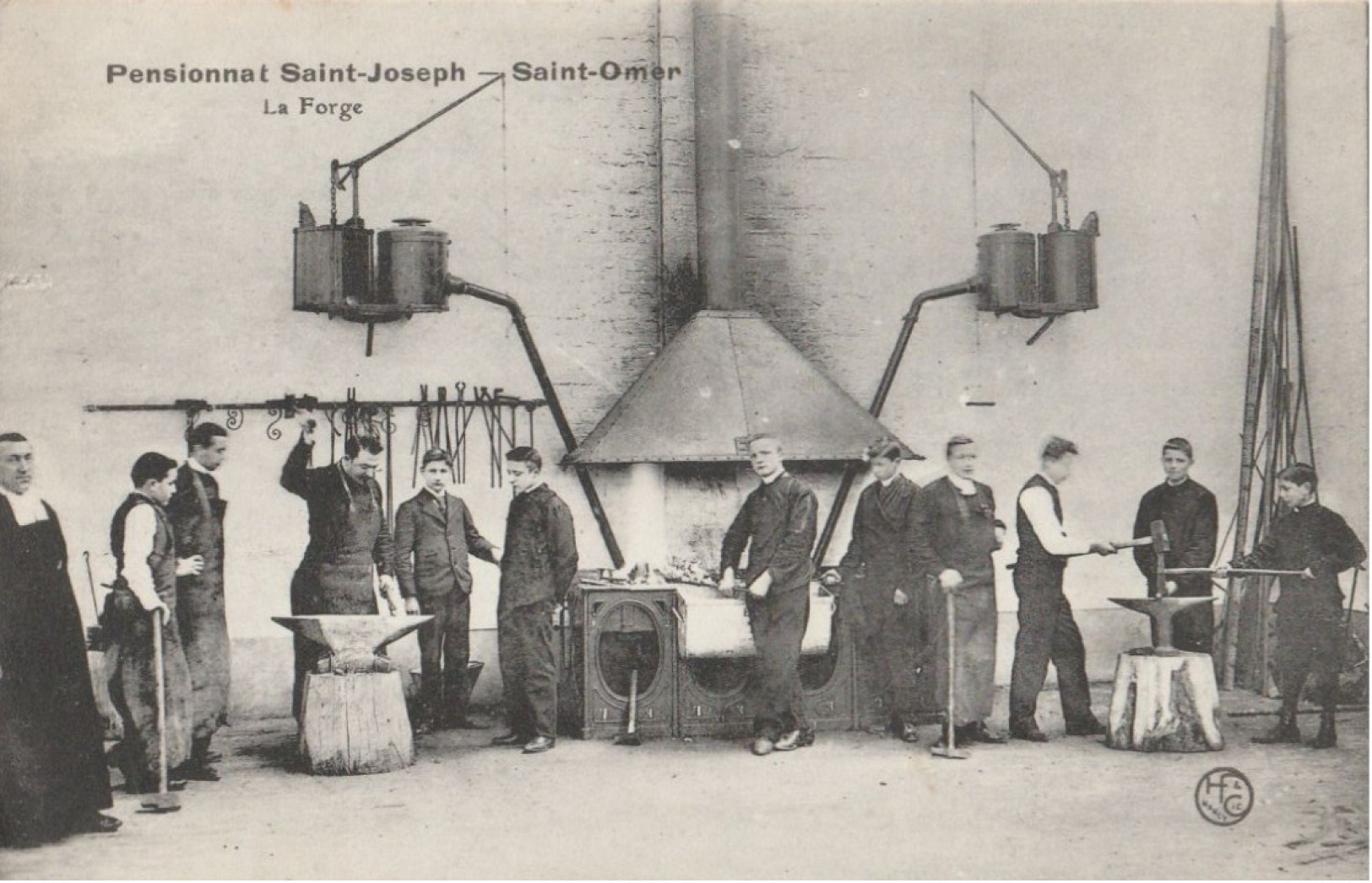 Sur la gauche, un prêtre surveille les élèves. Le professeur montre aux élèves comment se servir des outils pour forger.